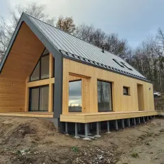 Nowy, drewniany dom pod klucz w lesie. Nowoczesna architektura, duże okna i taras. Idealny na tani, ekologiczny azyl.