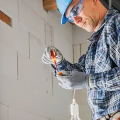 Elektryk w kasku i okularach montuje punkt elektryczny. Zastanawiasz się, ile za punkt elektryczny z kuciem?