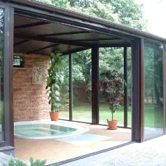 Relaks w domu: przestronny **ogród zimowy** z jacuzzi, kamienną ścianą i zielenią.