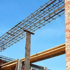 Gotowe nadproża wymiary: stalowa konstrukcja zbrojeniowa nad otworem w ceglanej ścianie, wsparta na drewnianym słupku.