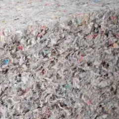 Gęsta, zbita masa z recyklingu, gdzie widać fragmenty kolorowych papierów i włókien. To ekologiczna celuloza, która może zyskać nowe życie.