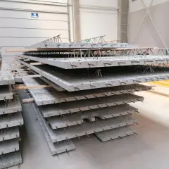 Stos prefabrykowanych płyt betonowych z widocznym zbrojeniem, przypominającym delikatny filigran.