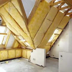 Ocieplenie stropu na poddaszu użytkowym z wełny mineralnej. Widoczne drewniane krokwie i okna dachowe.