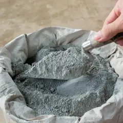 Łopata nabiera suchy beton. Kluczowe są właściwe proporcje składników do uzyskania mocnej mieszanki.