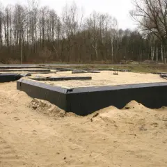 Fundament domu w piasku, otoczony czarną folią, zapewnia prawidłową izolację fundamentów.