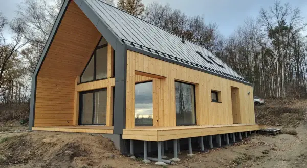 Nowy, drewniany dom pod klucz w lesie. Nowoczesna architektura, duże okna i taras. Idealny na tani, ekologiczny azyl.
