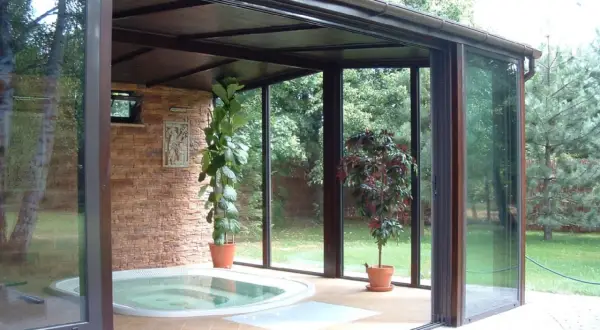 Relaks w domu: przestronny **ogród zimowy** z jacuzzi, kamienną ścianą i zielenią.