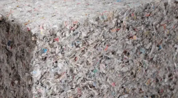 Gęsta, zbita masa z recyklingu, gdzie widać fragmenty kolorowych papierów i włókien. To ekologiczna celuloza, która może zyskać nowe życie.