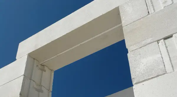 Białe nadproże nad drzwiami 90 cm, wykonane z bloczków z betonu komórkowego, na tle błękitnego nieba.