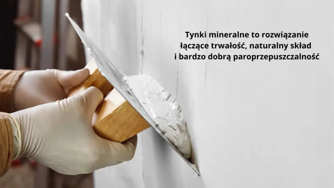 Ręce w rękawiczkach nakładają tynk na ścianę kielnią. To obrzutka, która zapewnia trwałość i paroprzepuszczalność.