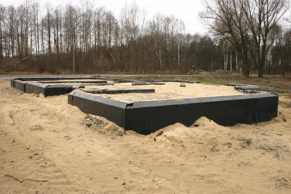 Fundament domu w piasku, otoczony czarną folią, zapewnia prawidłową izolację fundamentów.