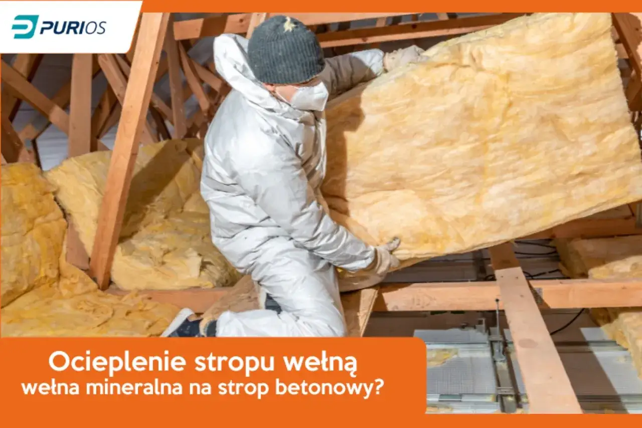 Ocieplenie stropu drewnianego wełną mineralną. Pracownik w kombinezonie montuje izolację na drewnianej konstrukcji poddasza.