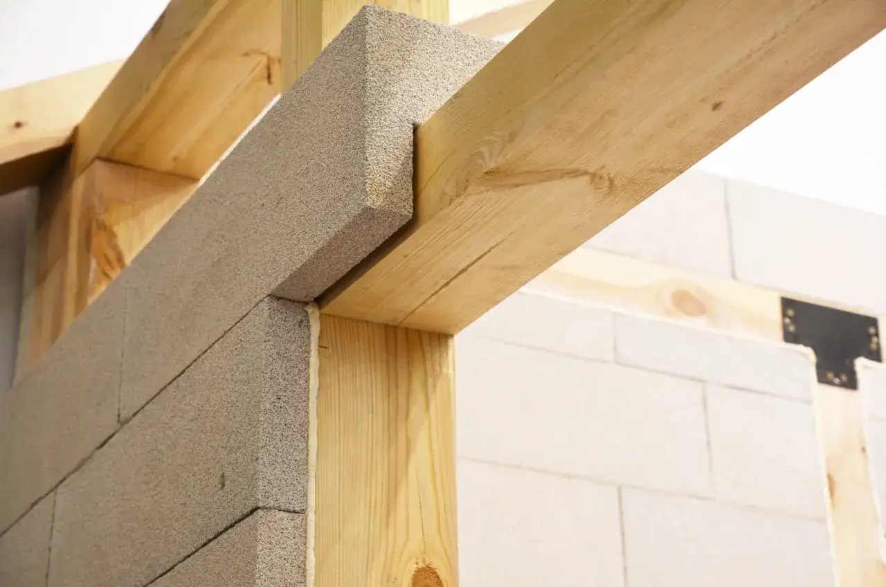 Drewniane nadproże nad drzwiami 90 cm, wykonane z bloczków betonowych i belek drewnianych, tworzy solidną konstrukcję.