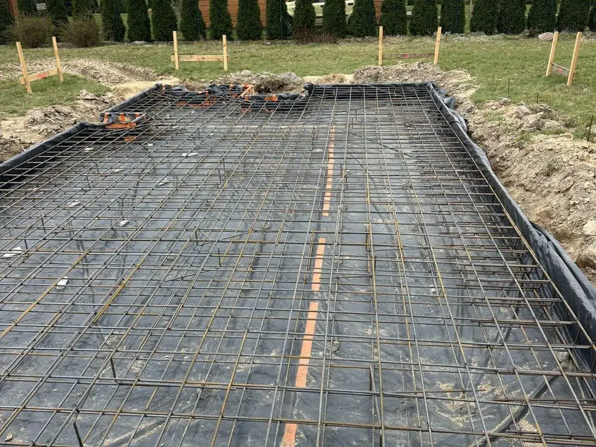 Siatka zbrojeniowa na płycie fundamentowej, gotowa na zalanie betonem. Wybór odpowiedniego betonu na płytę fundamentową jest kluczowy dla trwałości budowli.