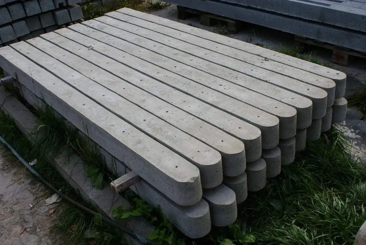 Ułożone stosy betonowych słupków, gotowe do wysyłki. Sprawdź nasz słupki betonowe cennik!