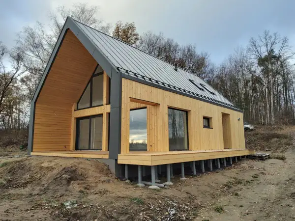 Nowy, drewniany dom pod klucz w lesie. Nowoczesna architektura, duże okna i taras. Idealny na tani, ekologiczny azyl.