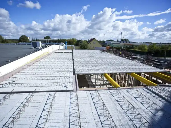 Budowa nowego stropu nad halą przemysłową. Metalowe kratownice i zbrojenie czekają na beton.