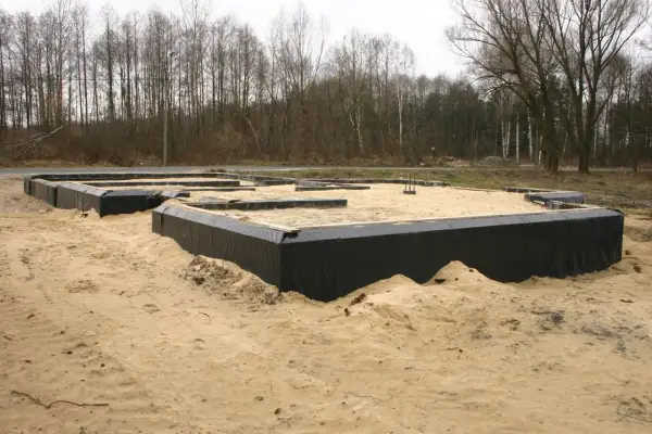 Fundament domu w piasku, otoczony czarną folią, zapewnia prawidłową izolację fundamentów.